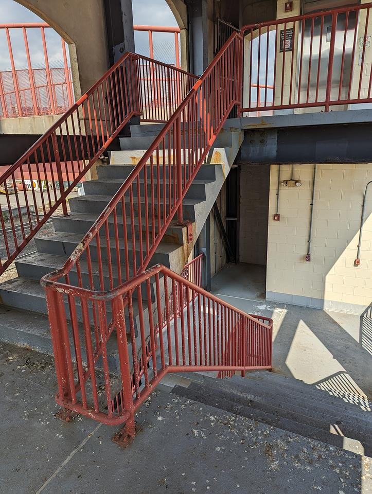 Concrete staircase with metal hand rail, covered in bird droppings.