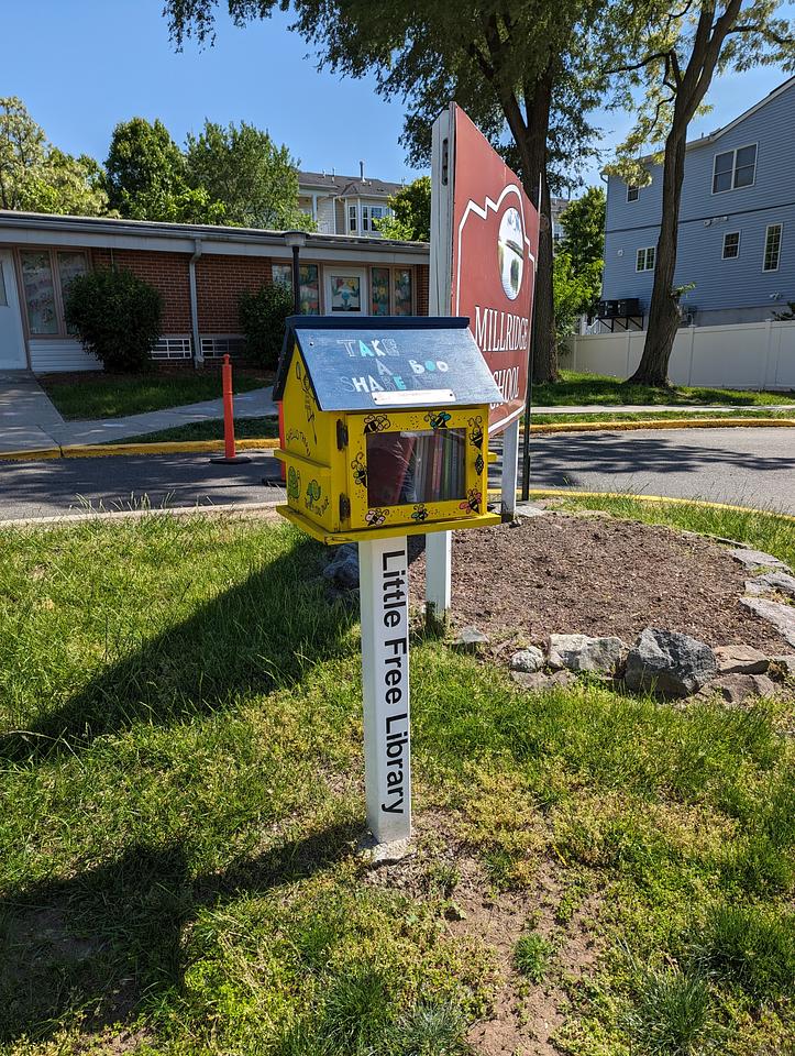 Little Free Library outside the Millridge School. Yellow with a blue roof.