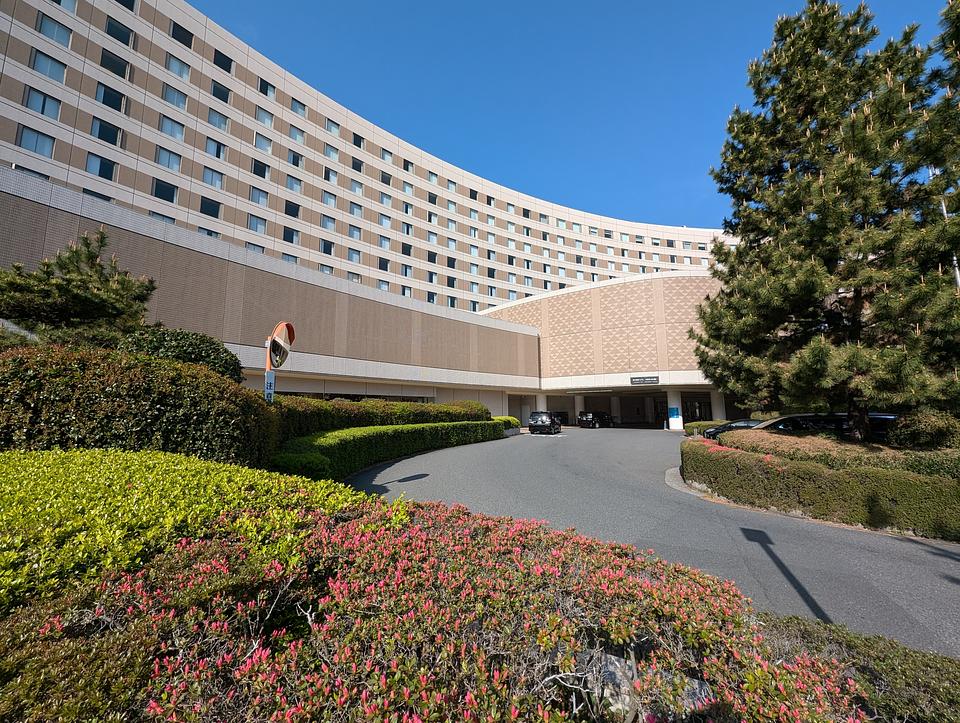 Exterior view of the Hilton hotel at Tokyo Bay.  The hotel is several shades of tan and 7-8 floors of windows are visible in addition to the driveway.