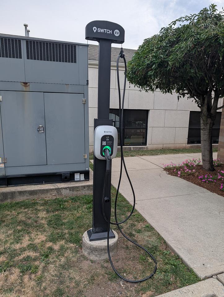 SWTCH EV Charger installed in the grass next to a parking space.