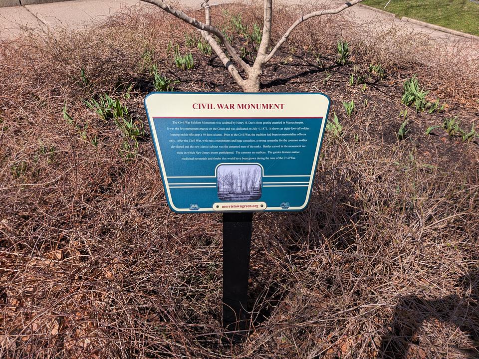 Sign describing the Civil War Monument on the Morristown Green. Behind the sign, a bunch of winter bushes are visible.